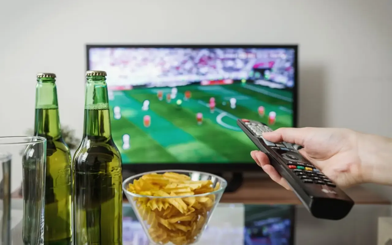 Télécommande pointée vers un téléviseur diffusant un match de football, dans un salon