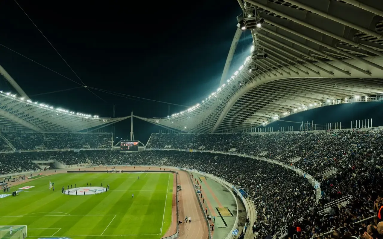 Vue large de tribunes pleines dans un stade de football en nocturne