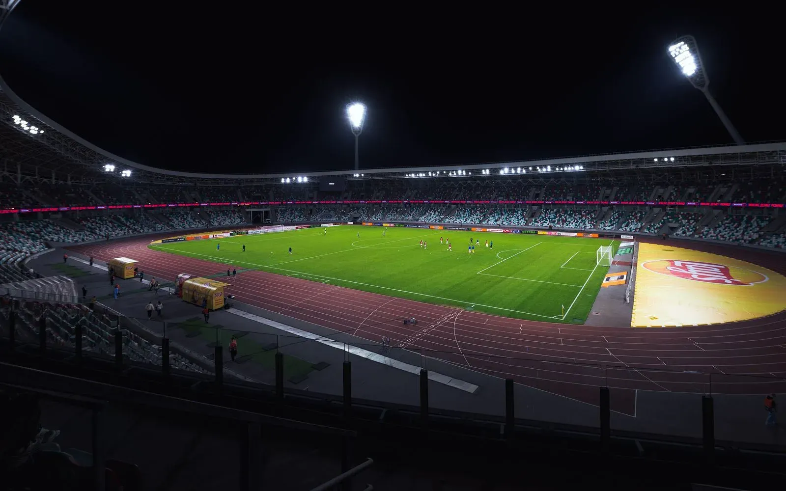 Stade de football vide éclairé par ses projecteurs, pelouse déserte en nocturne