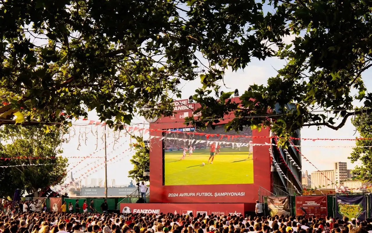 Foule rassemblée devant un écran géant en fan zone pour regarder un match de football