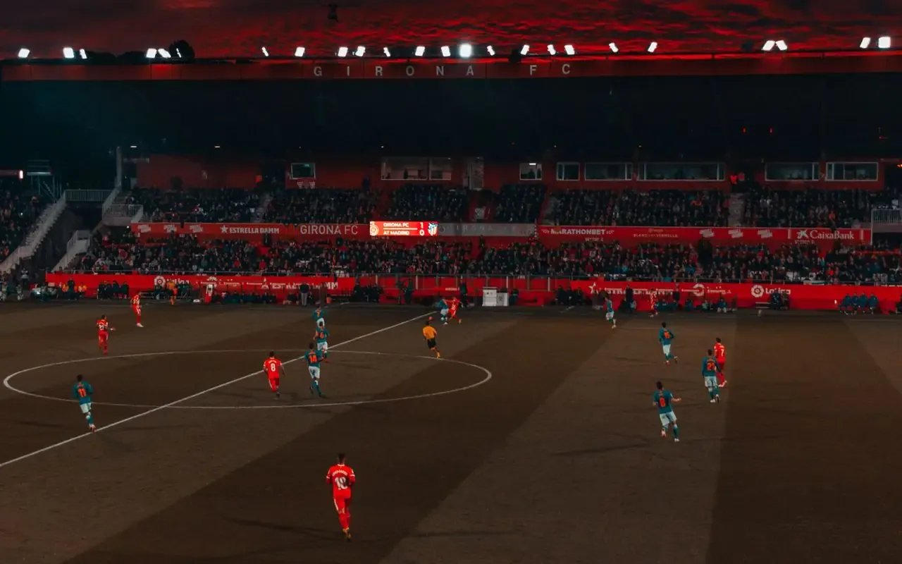 Match de football en nocturne, panneaux publicitaires des sponsors visibles en bord de terrain